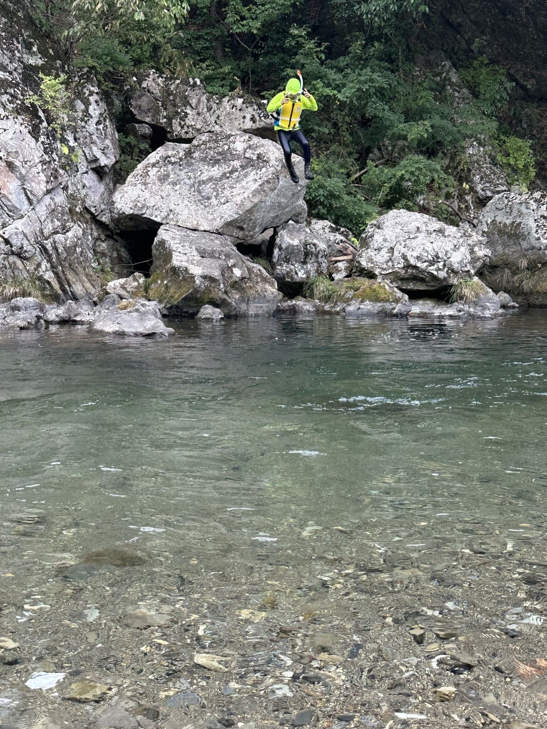 清流のほとりの岩場に立つ子ども